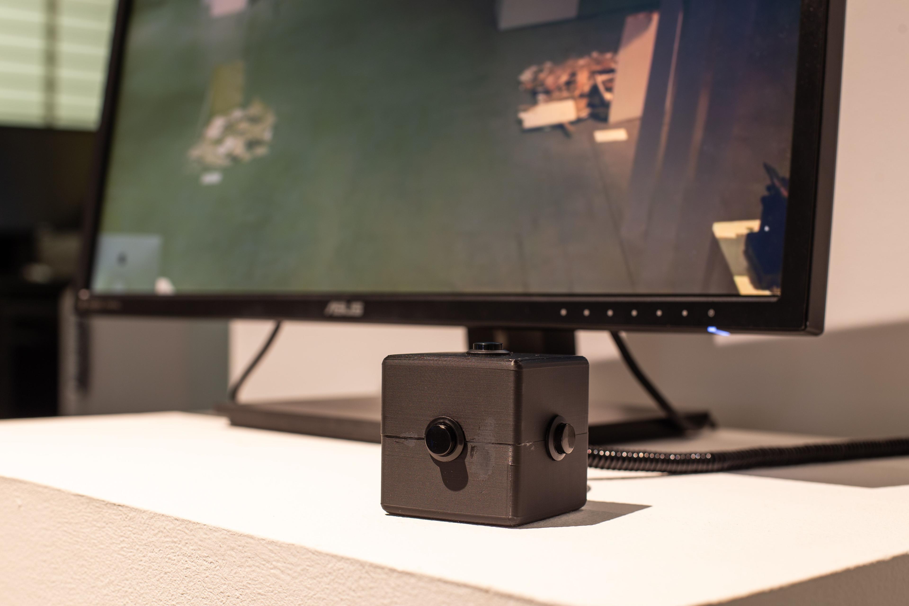 A close up of the cube-shaped controller, with a single button at the center of each face.