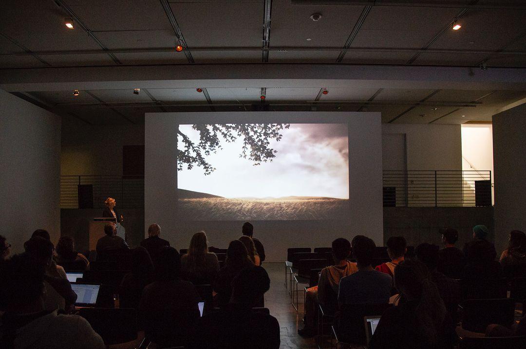 People watching a movie projected on a large wall.