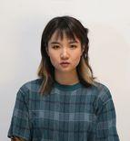 A young person with East Asian ethnicity, wearing a short-sleeve sweater, looking at the camera. 